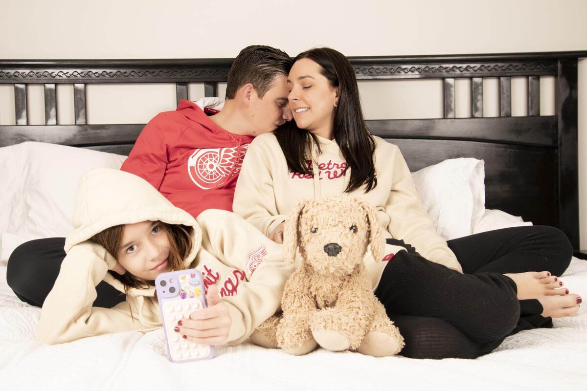a family of three sitting on a huge king bed