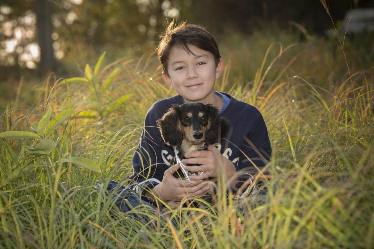boy sitting in grass with his puppy